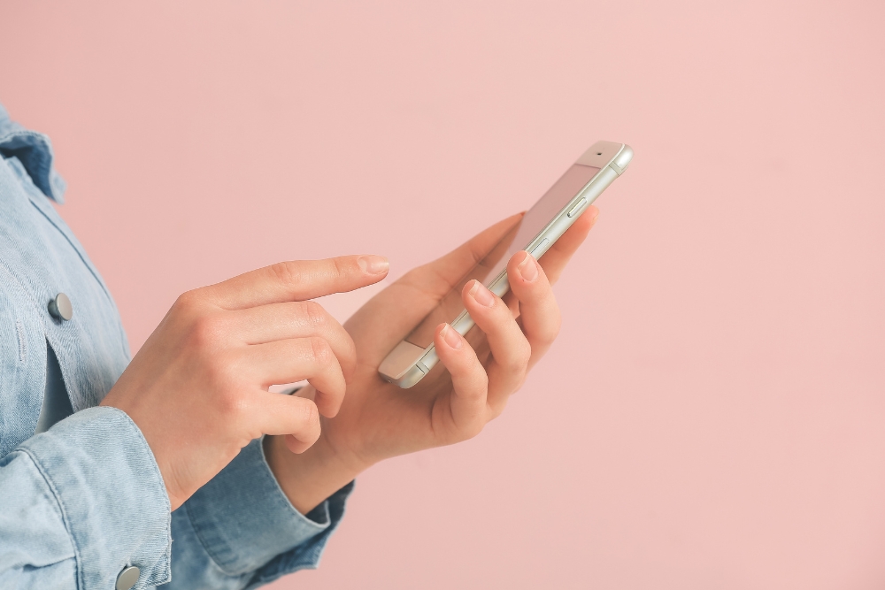 Person holding a smartphone with a pink background, showcasing tips on how to increase mobile website speed
