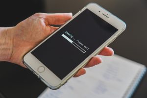 Hand holding a smartphone displaying a loading screen with the text 'Loading... Please Wait', highlighting issues with mobile website speed