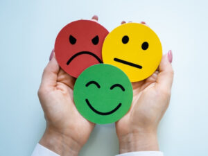 a man holding a emjoi that indicates a smile, a half smile and a angry reacting indicating customer testimonial